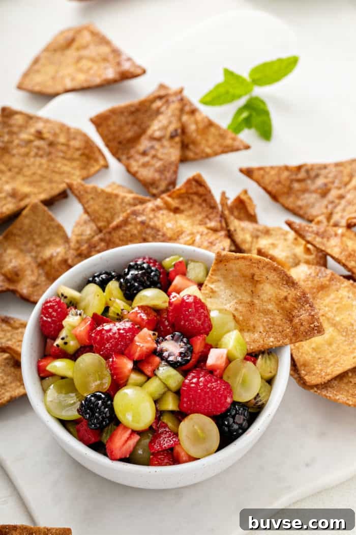 Fresh Fruit Salsa Recipe with Lime and Cilantro 2 Cinnamon chip in a bowl of fruit salsa, with more cinnamon chips in the background.