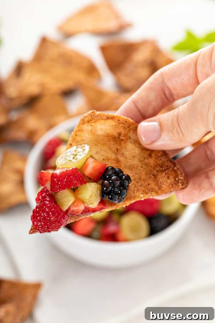 Fresh Fruit Salsa Recipe with Lime and Cilantro 10 Hand holding up a cinnamon chip with a scoop of fruit salsa on it.