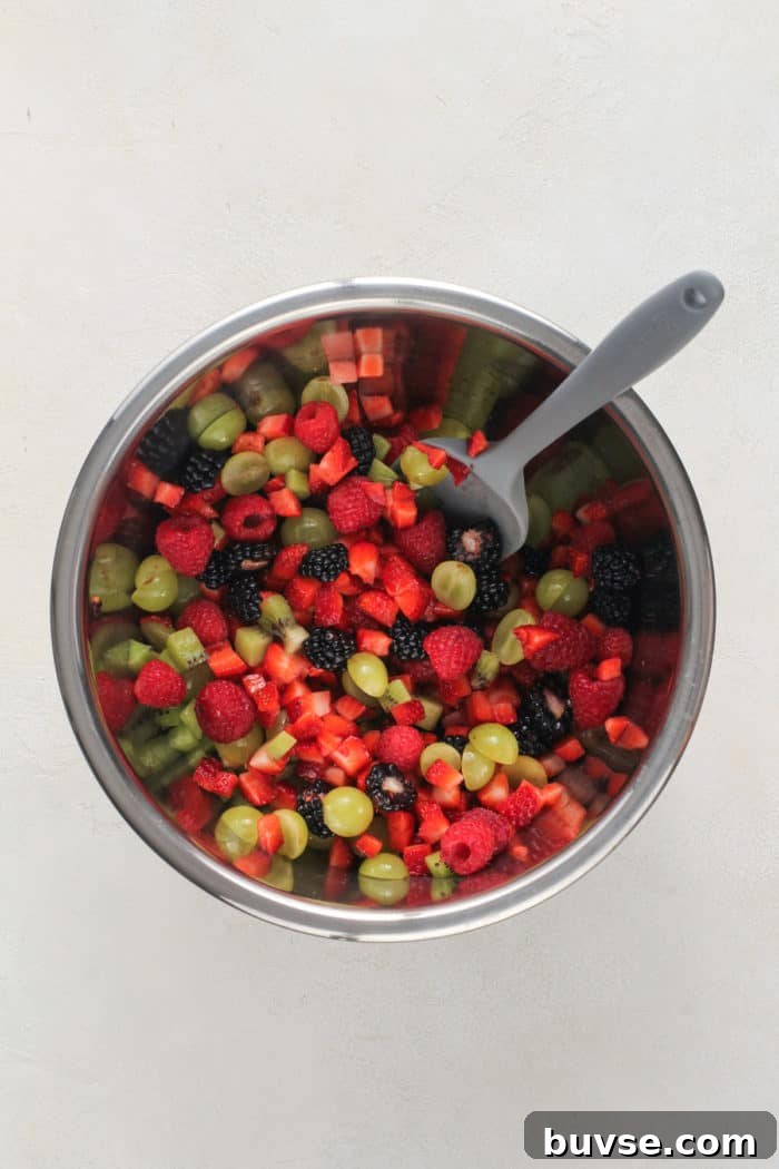 Fresh Fruit Salsa Recipe with Lime and Cilantro 6 Spatula stirring diced fresh fruit in a metal bowl.