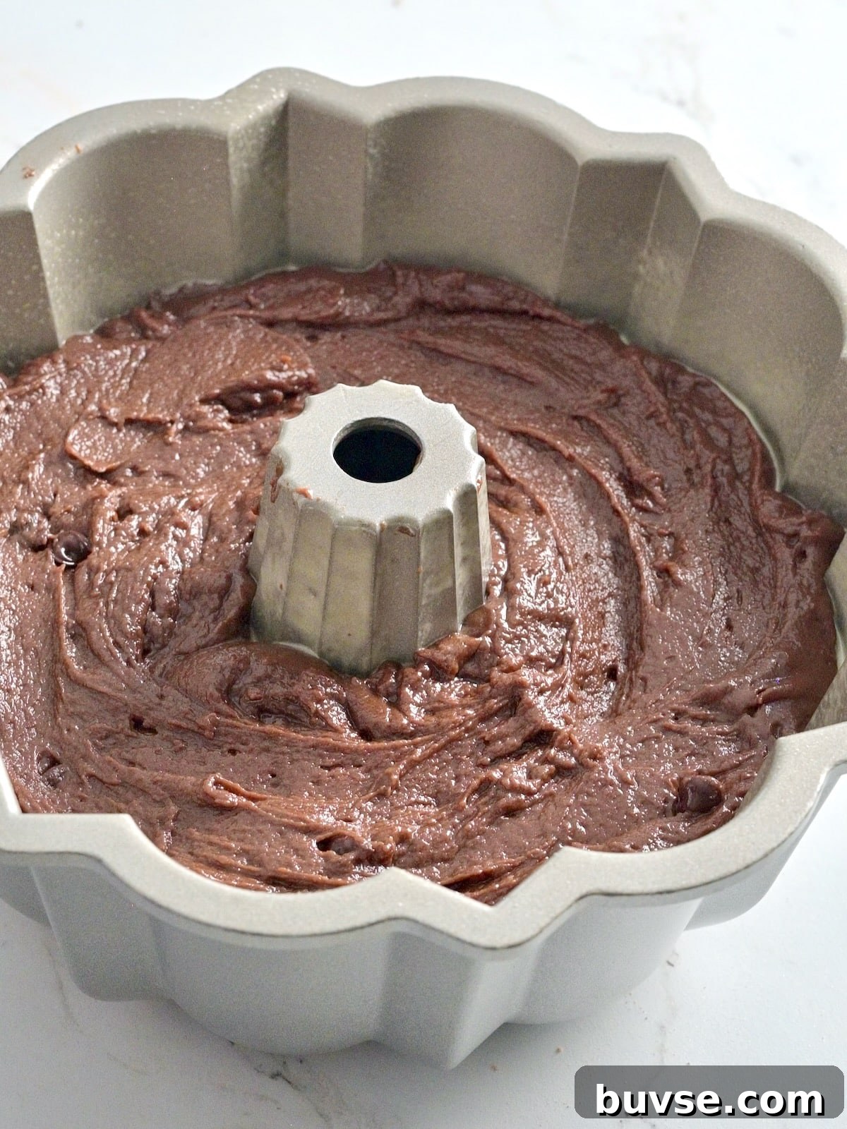 Moist Double Chocolate Chip Bundt Cake 8 Chocolate bundt cake batter smoothed into a light silver Nordic Ware bundt pan before baking.