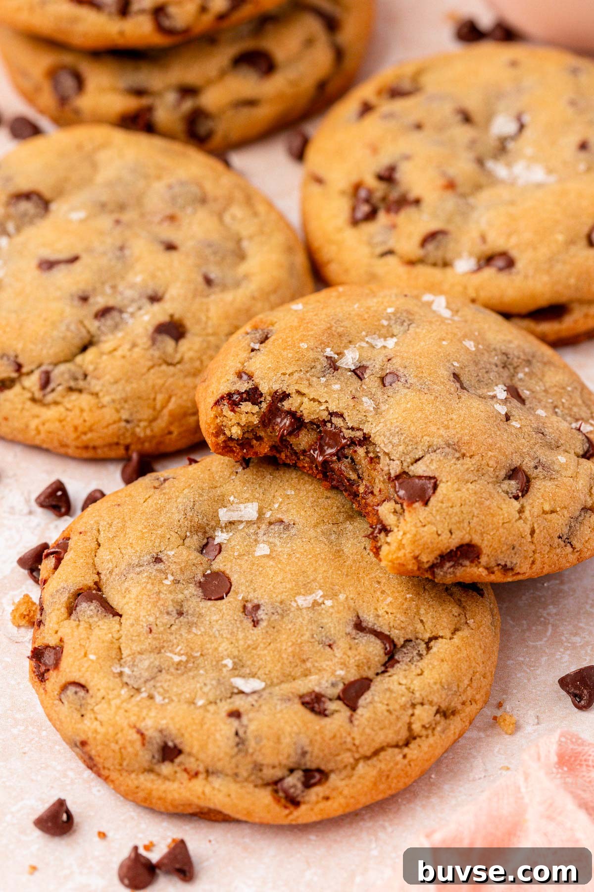 Close up of cookies on a counter layered on top of each other. One is missing a bite.