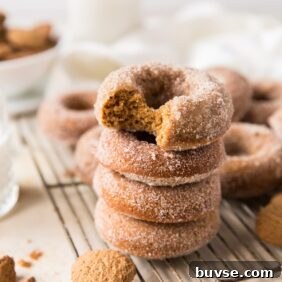 Stack of four gingerbread donuts on wire rack; top donut with a bite taken out