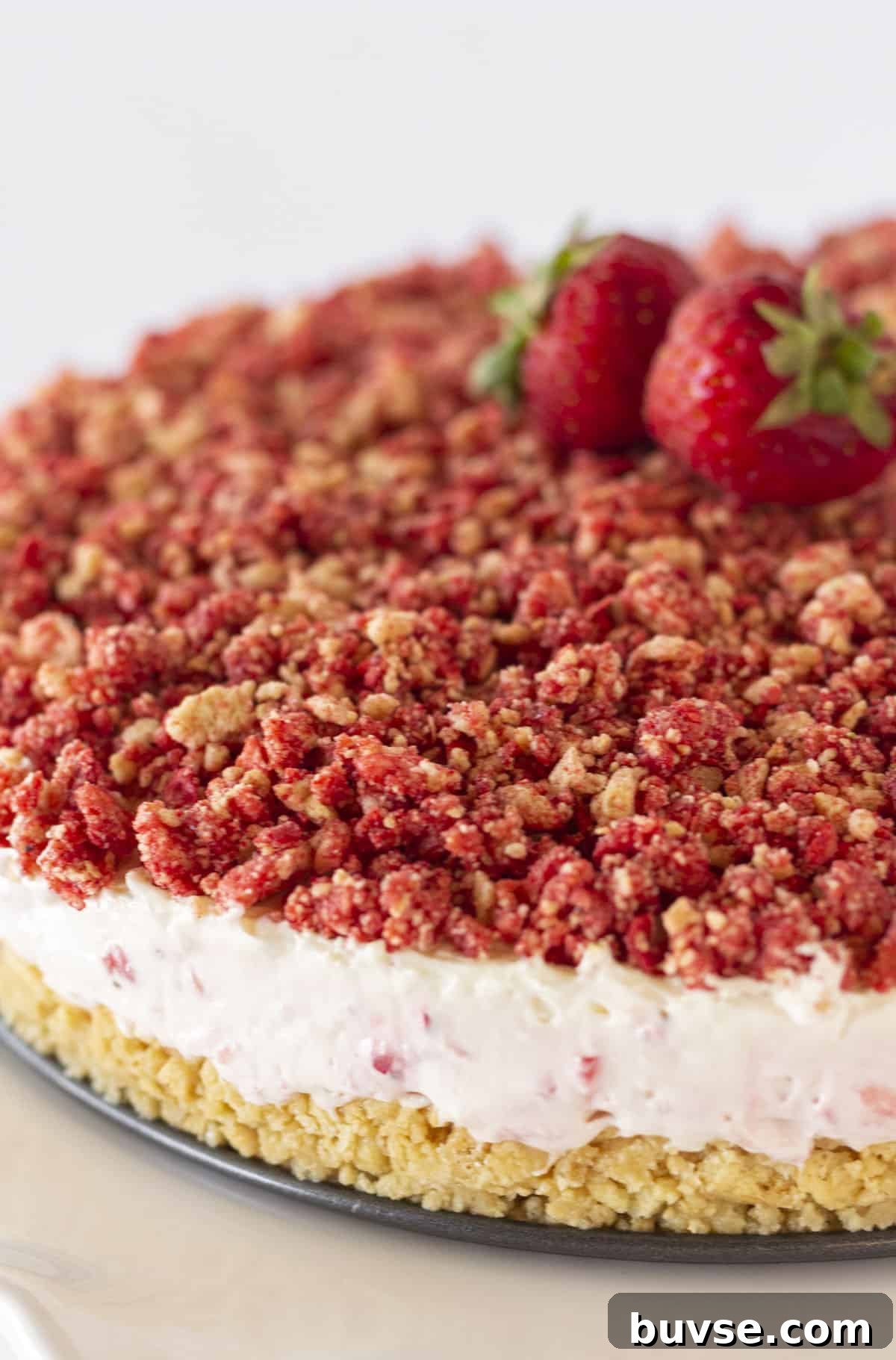 No-Bake Strawberry Crunch Cheesecake Recipe 7 A whole strawberry crunch cheesecake with fresh strawberries on top.
