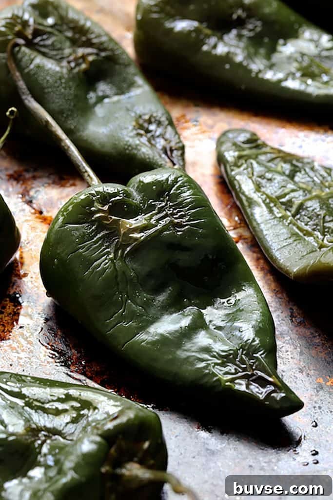 Photo of roasted poblano peppers on baking sheet.