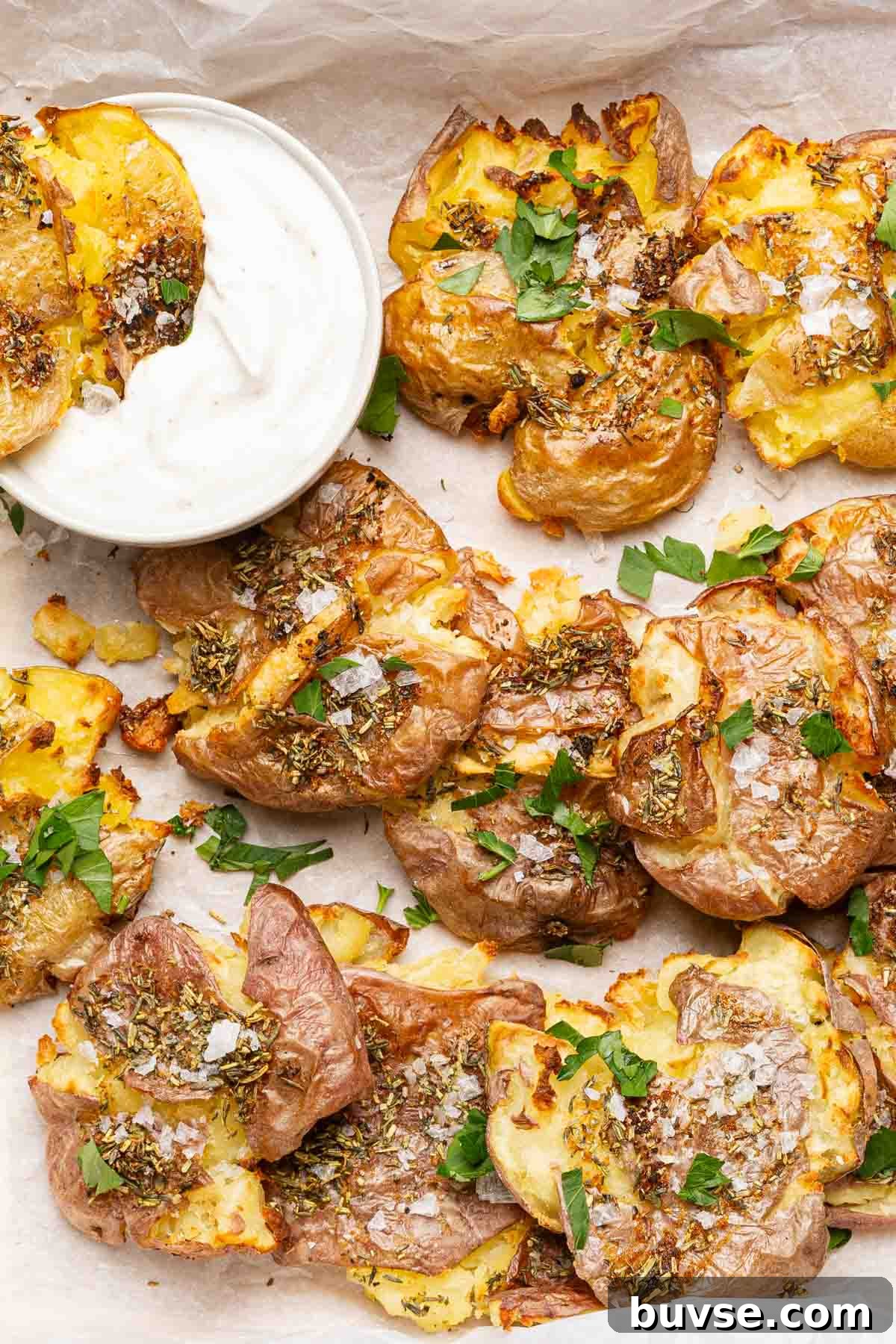 air fryer smashed potatoes with side of sour cream and garnished with parsley.