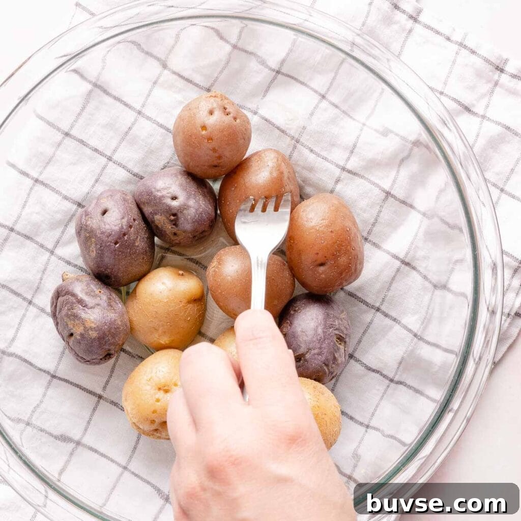 mini potatoes in glass bowl with fork piercing one potato.