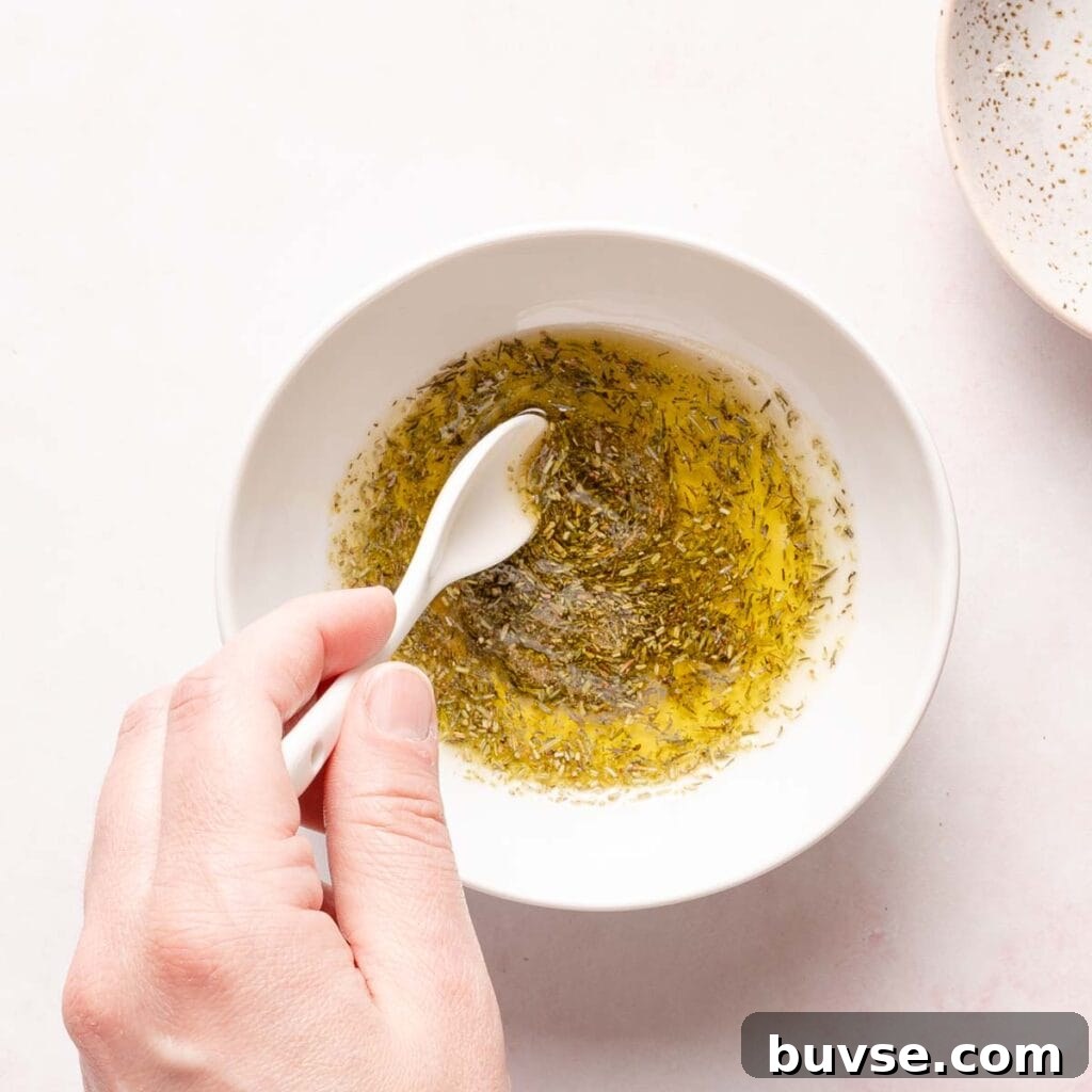 spoon mixing dried herbs into oil in small bowl.