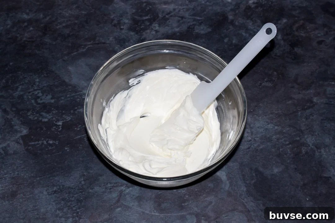 Softened cream cheese in a glass bowl with a spatula
