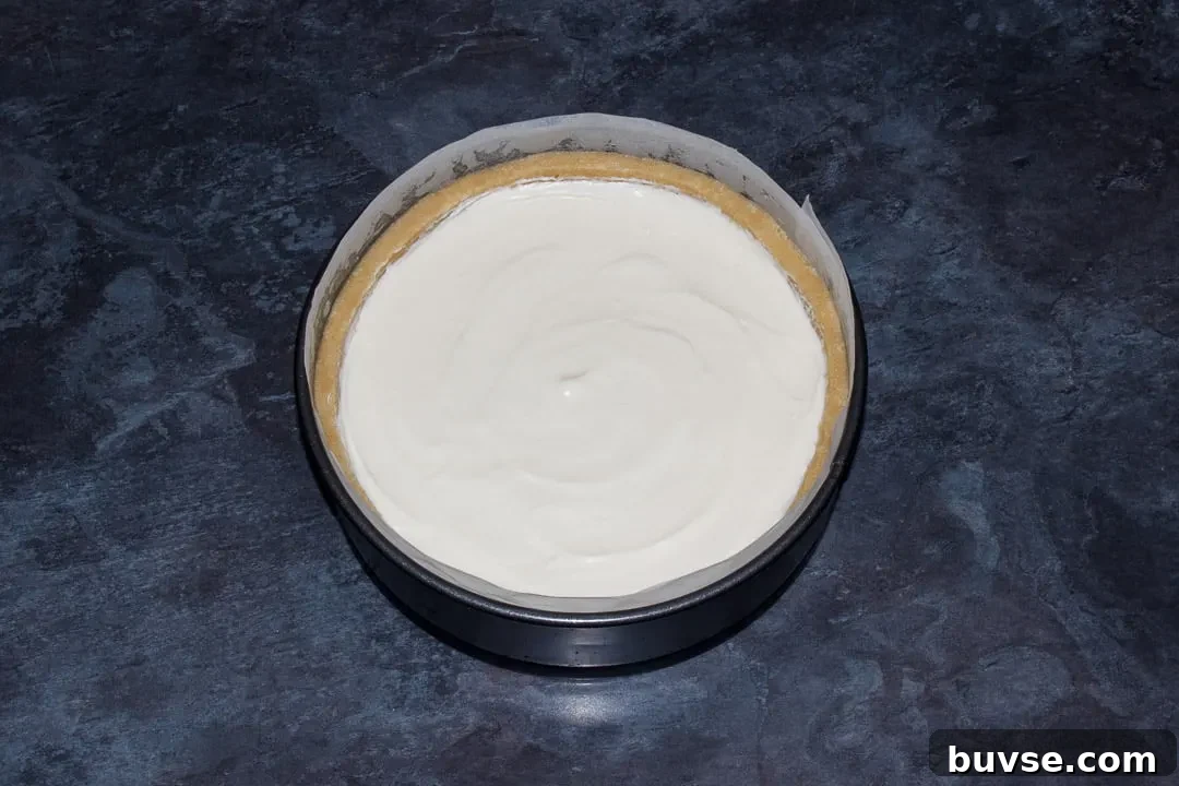 No bake vanilla cheesecake in a lined springform pan ready for setting in the fridge