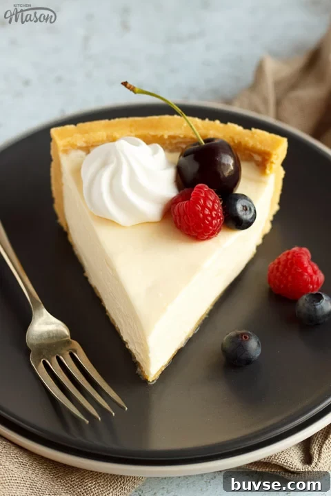 A slice of no bake vanilla cheesecake on a grey plate with a fork, topped with mixed berries