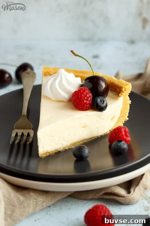 A slice of no bake vanilla cheesecake on a grey plate with a fork, topped with mixed berries