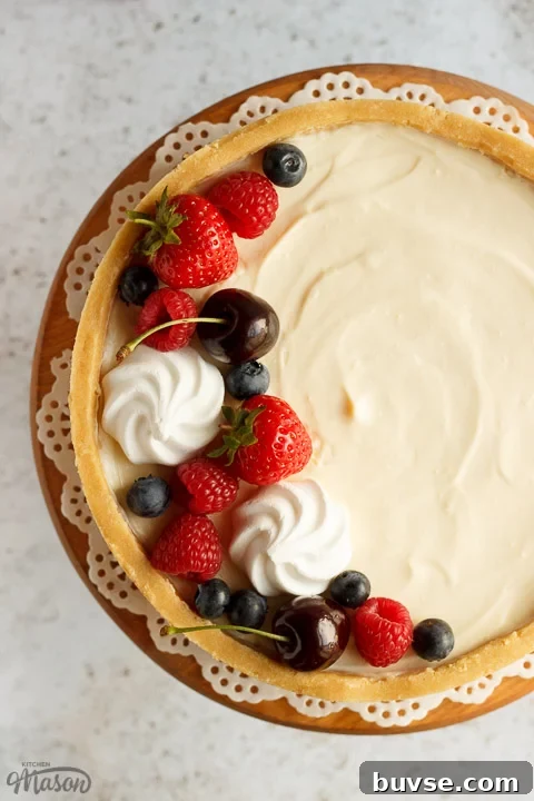 A no bake vanilla cheesecake on a cake stand topped with mixed berries