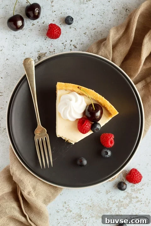 A slice of no bake vanilla cheesecake with a bite taken out of it on a grey plate with a fork, topped with mixed berries