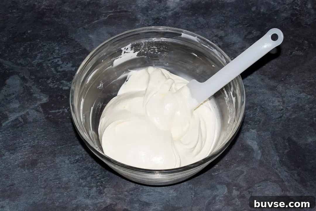 No bake vanilla cheesecake filling in a glass bowl with a spatula.