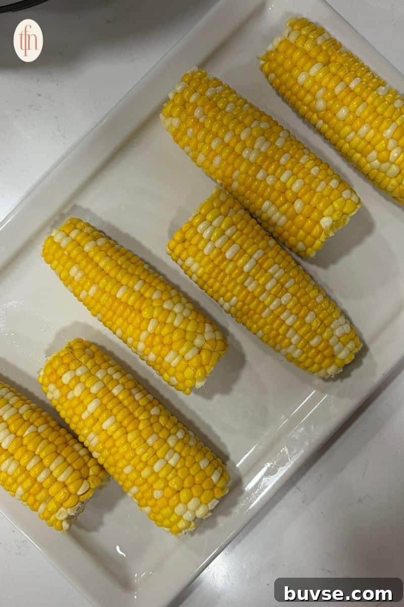 corn on the cob resting on a white serving tray.