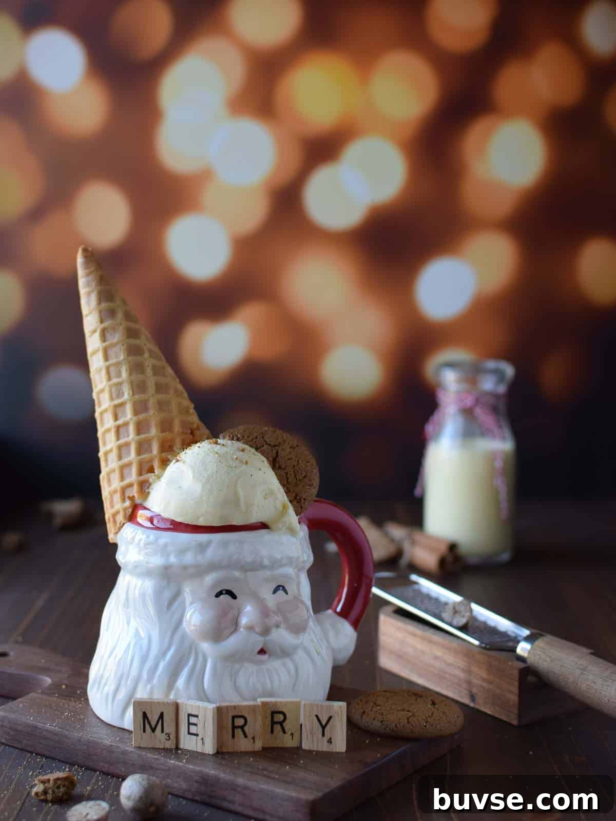 Eye level view of egg nog ice cream in a santa claus mug with a cone on it's head on brown surface with glittery background