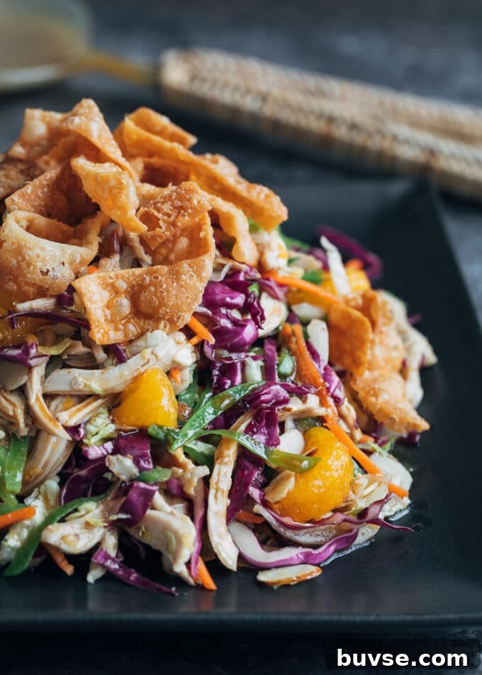 mandarin orange chicken salad with crispy wonton strips on a black plate 