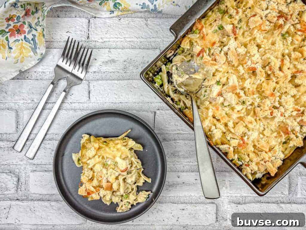Top-down shot of Tuna Noodle Casserole on a dish with a small portion on a black plate.