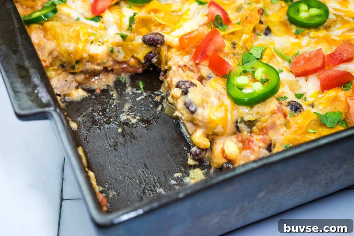 A close-up of a partially eaten cheesy Mexican chicken casserole in a baking dish.
