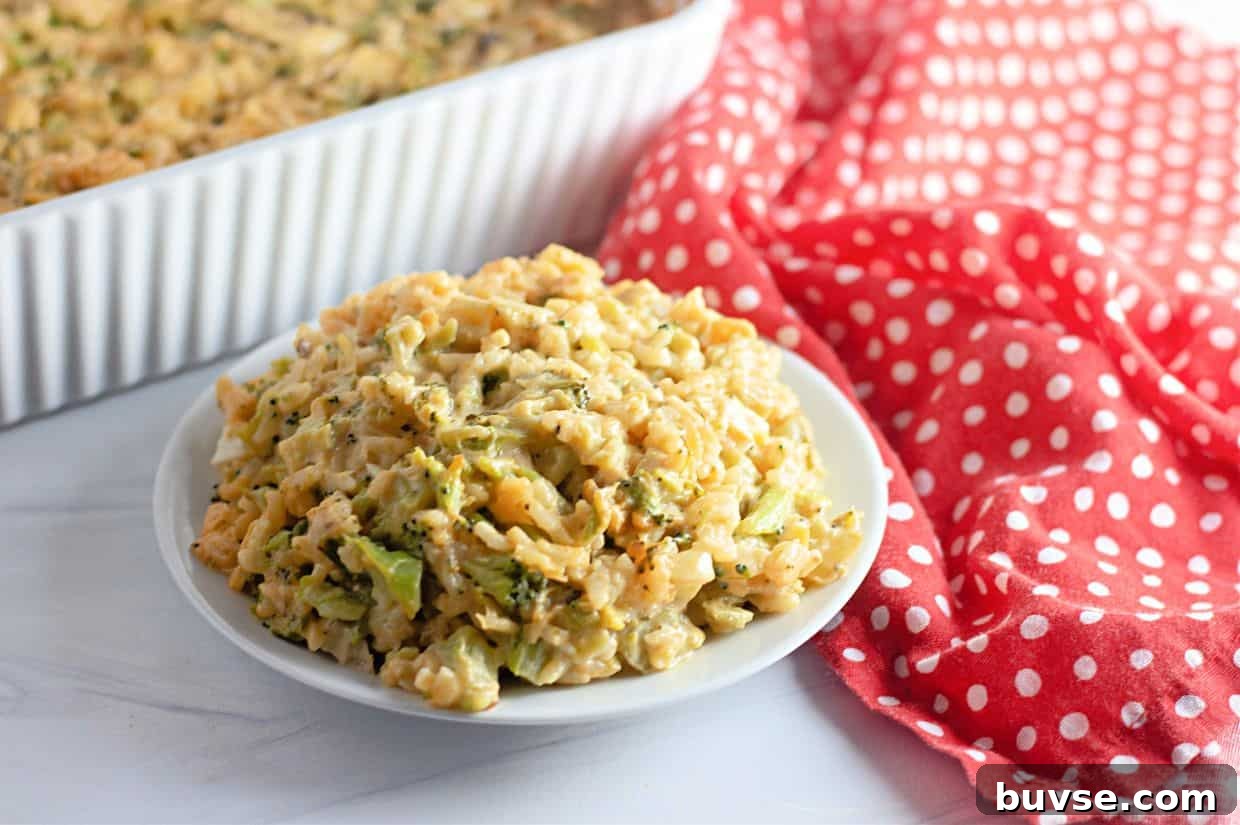 A plate of Easy Cheesy Broccoli Rice Casserole sits on a white surface next to a red and white polka dot cloth, with a baking dish in the background.