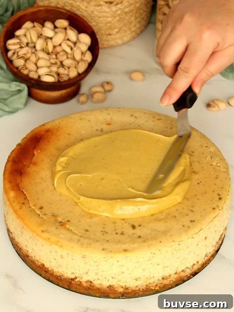 Spreading pistachio paste over cheesecake