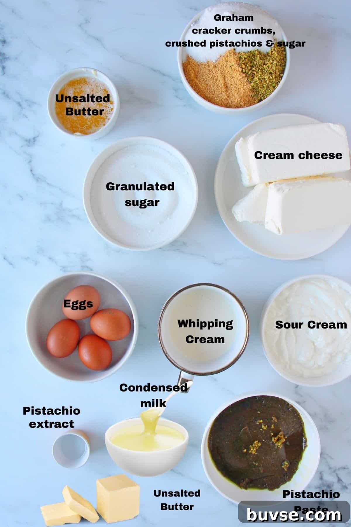 Ingredients for pistachio cheesecake laid on marble background.