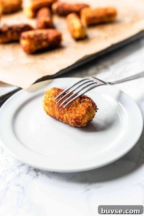 Crispy Potato Croquettes Recipe for Golden Homemade Bites 4 Homemade potato croquette on a white plate with a fork. Looks very tasty.