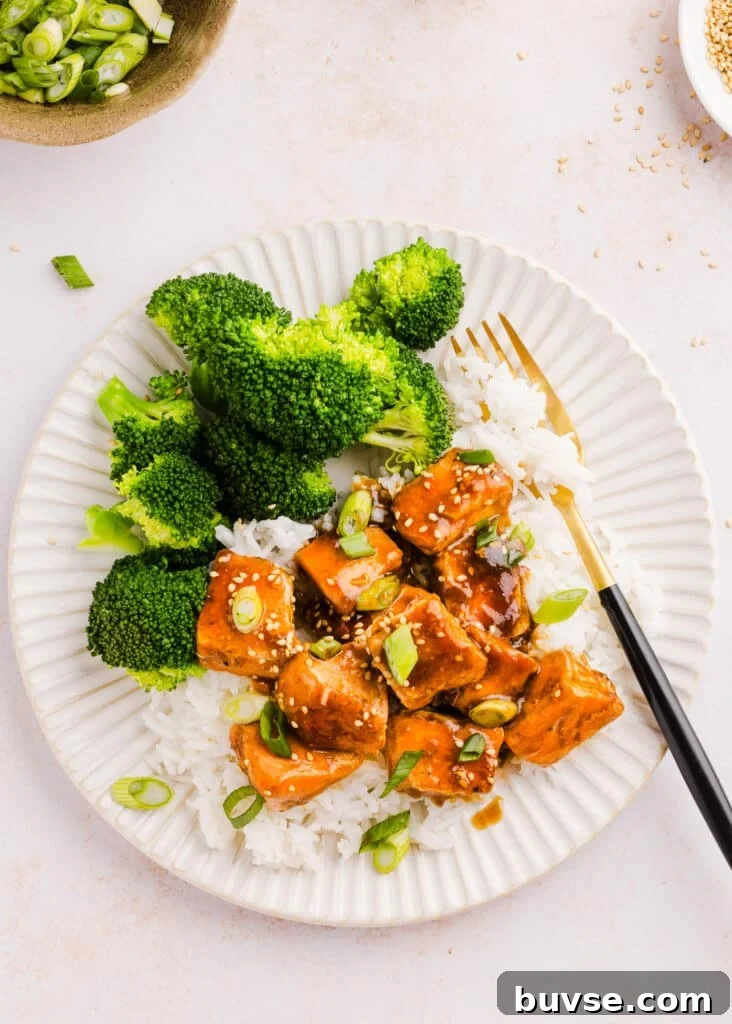 Teriyaki salmon bites served with broccoli and rice on a plate.