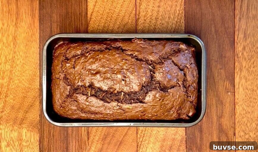 Double Chocolate Zucchini Bread 9 Baked bread in loaf pan, on a wooden table.