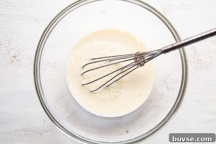 milk and egg mixture with a whisk in a glass bowl.