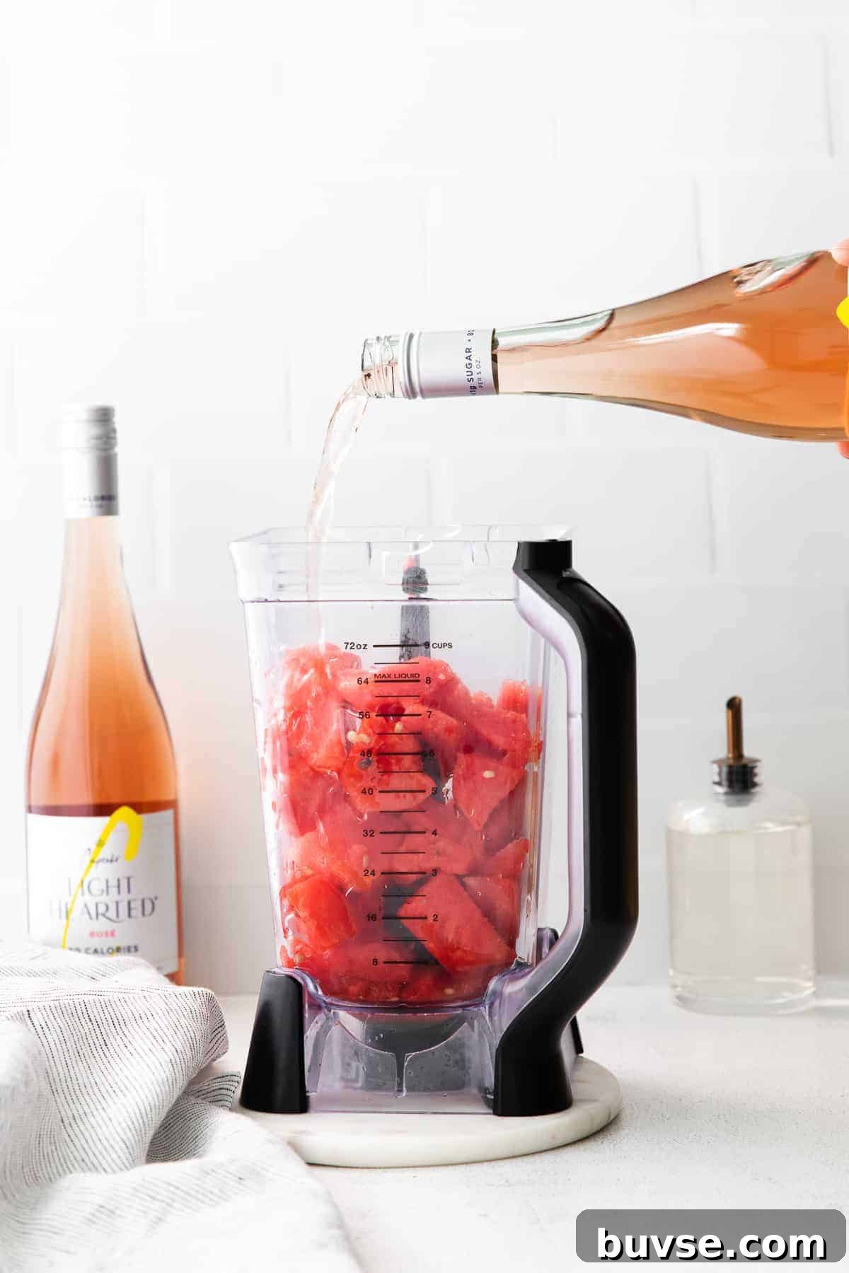 pouring a bottle of rosé into a blender with frozen watermelon