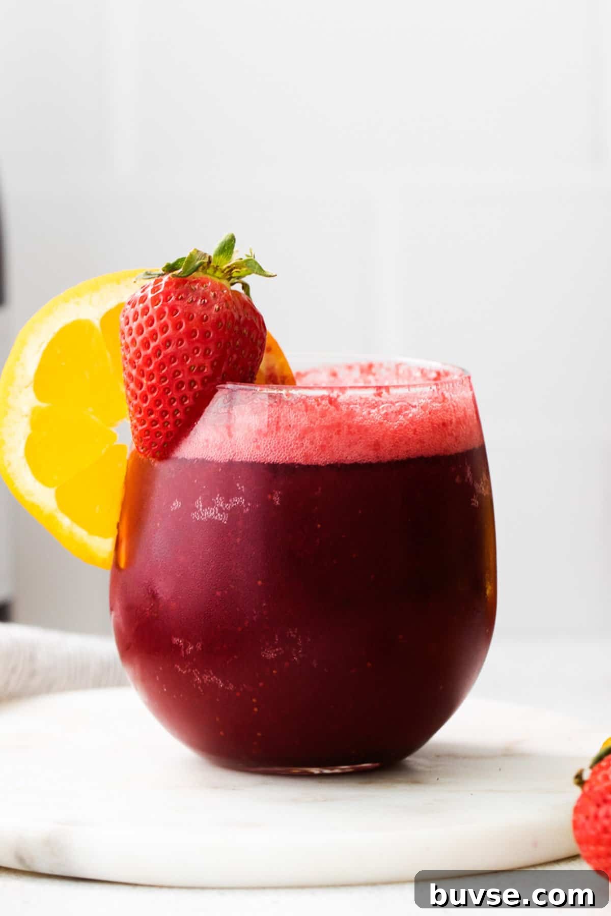 a red drink with a slice of lemon on top of it.