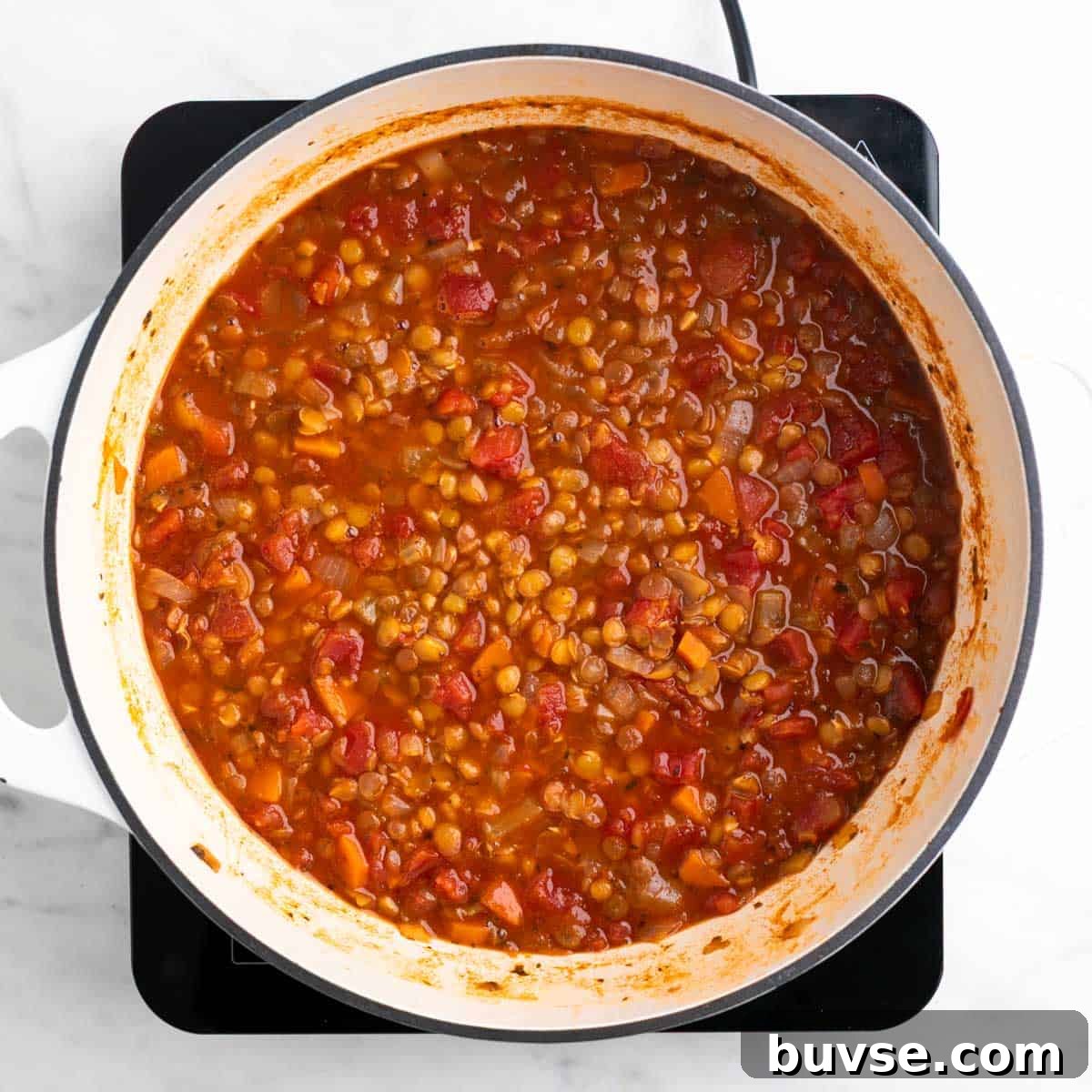 Cooked vegan lentil soup in a large pot before adding salt and black pepper.