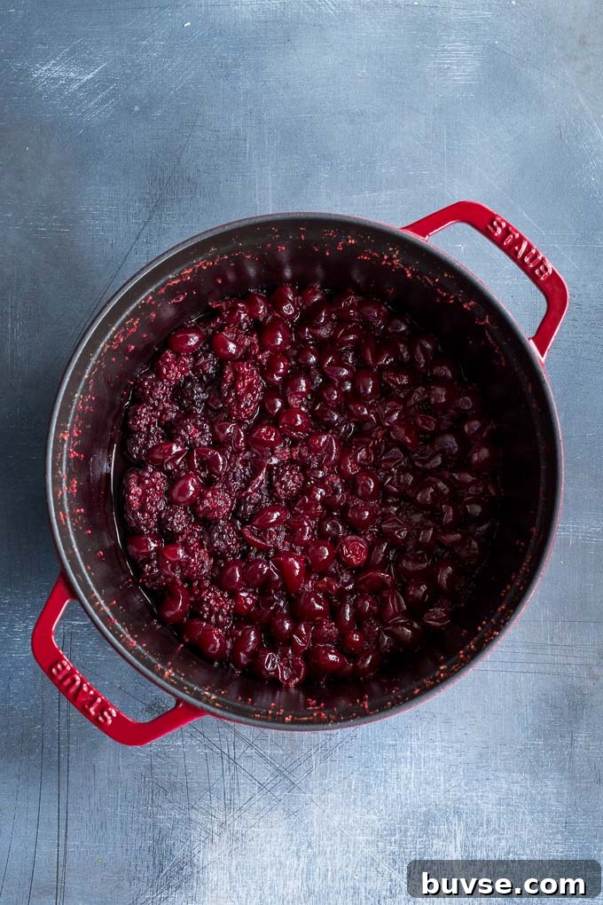 Overhead view of softened fruit for the cranberry sauce in a large pot.