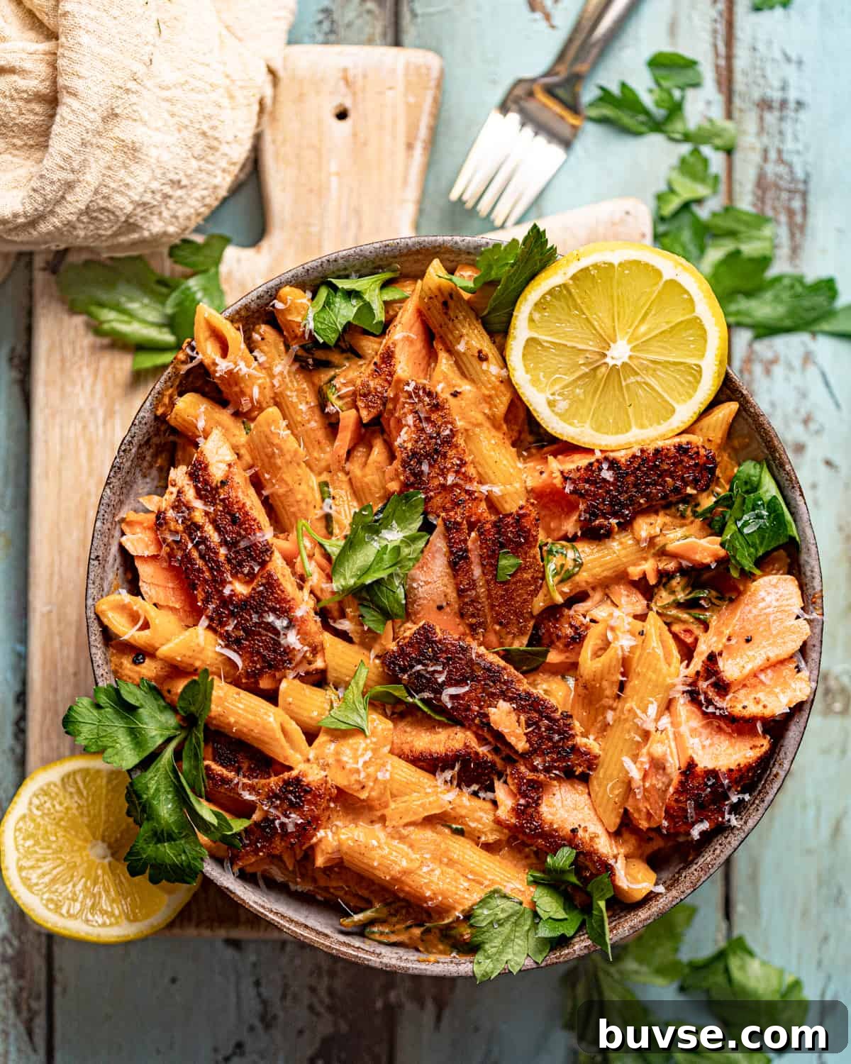 cajun salmon pasta in a bowl on top of a serving board.