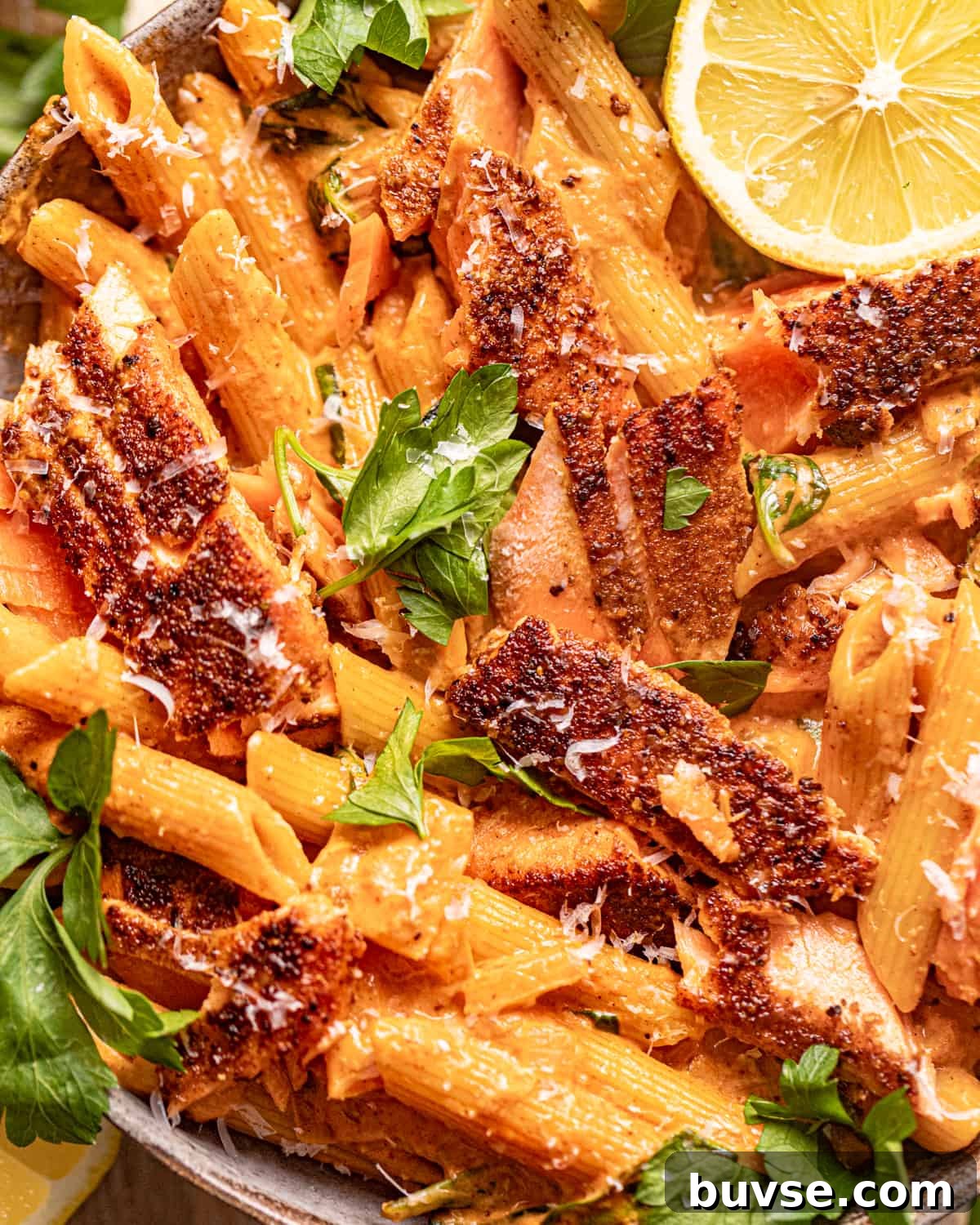 up close photo of cajun salmon pasta in a bowl garnished with fresh parsley.