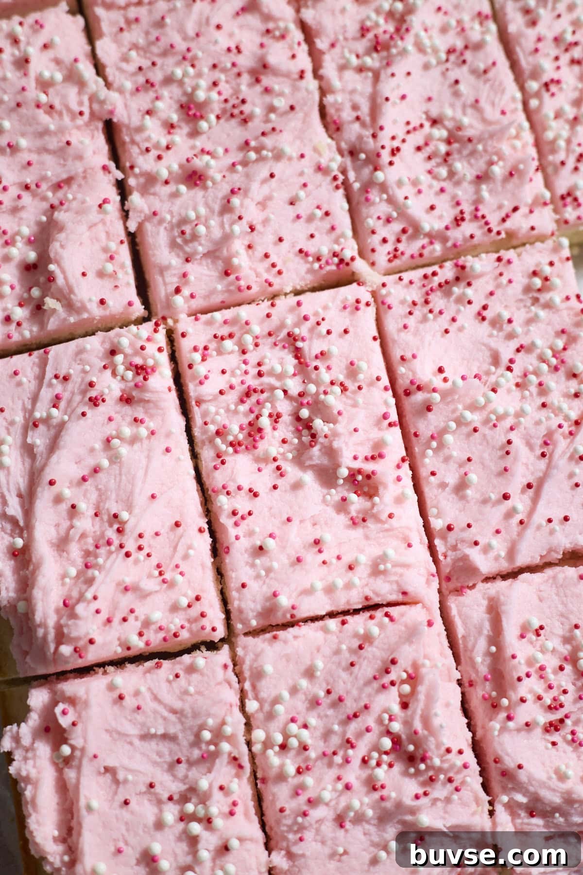 Sliced sugar cookie bars with pink icing.