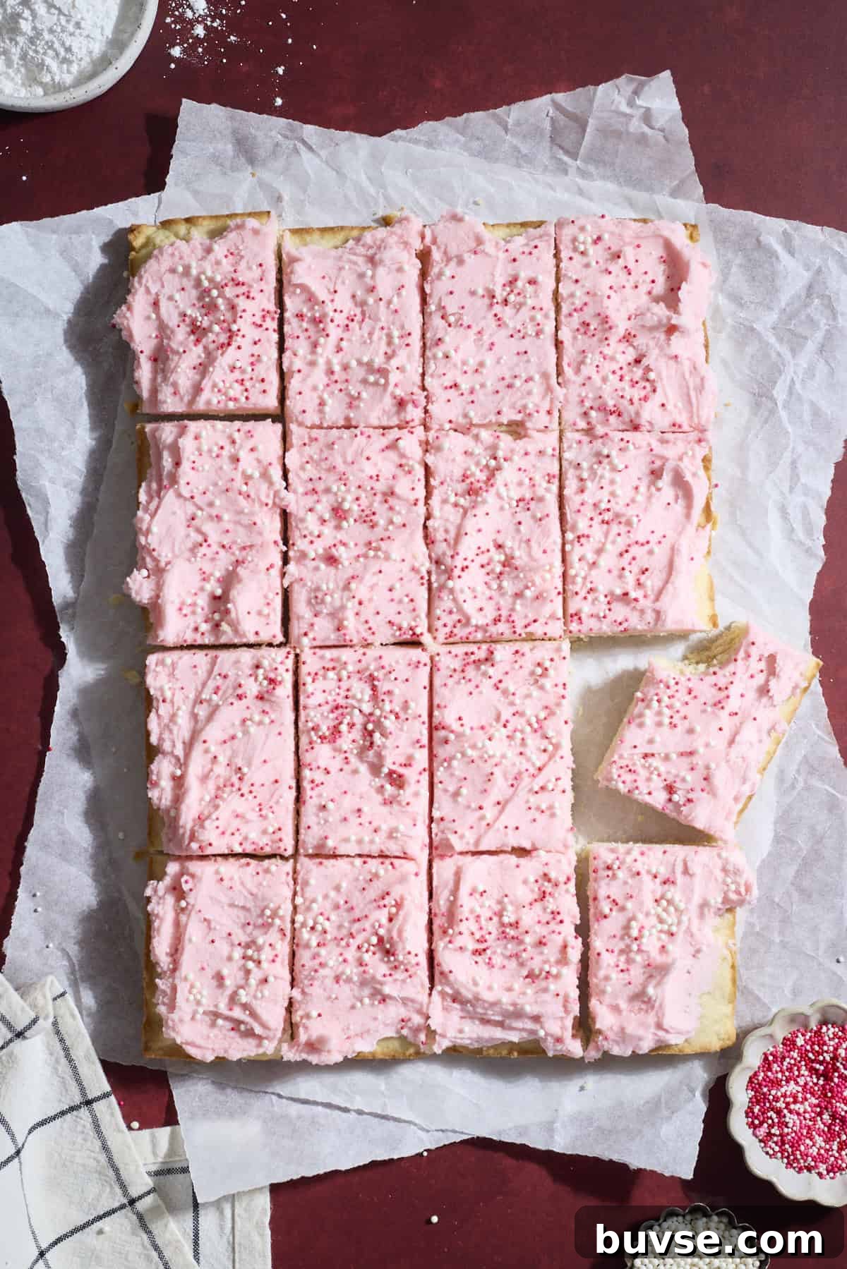 Sliced sugar cookie bars with pink icing.