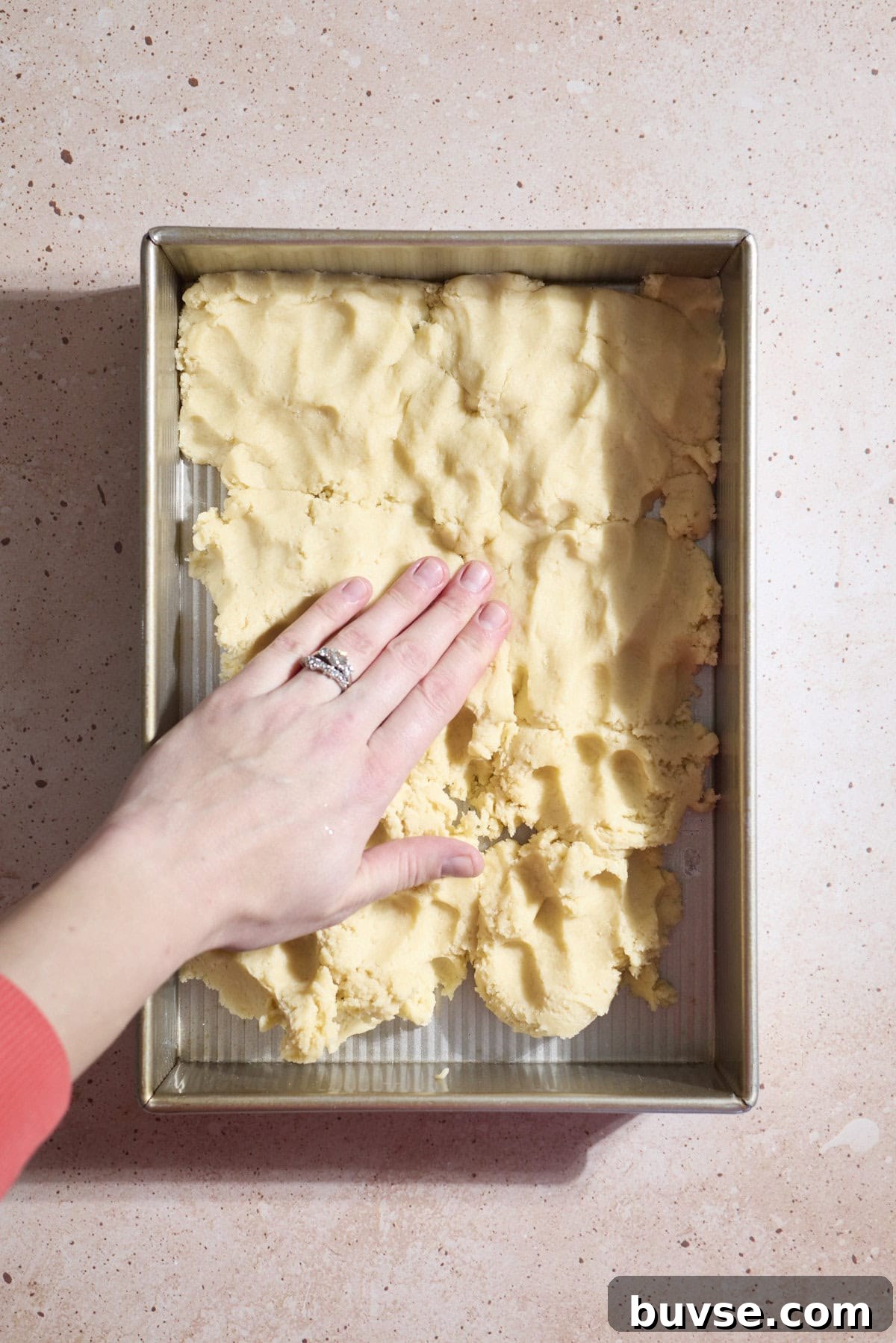 Dough being pressed into a 9x13-inch baking pan.