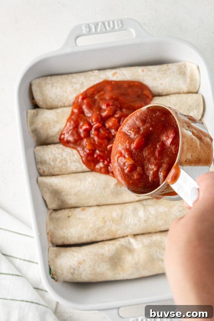 Flavorful Dairy-Free Chicken Enchiladas Recipe 11 Pouring over the enchilada sauce before going into the oven.