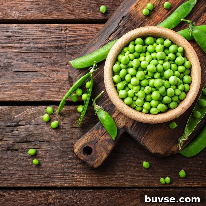 Green Peas in wooden bowl on top of wooden table
