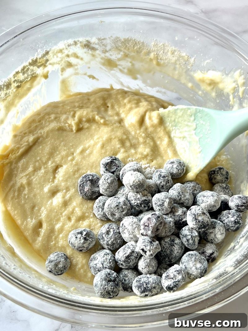 Dry ingredients combined with wet ingredients, buttermilk, and frozen blueberries. 