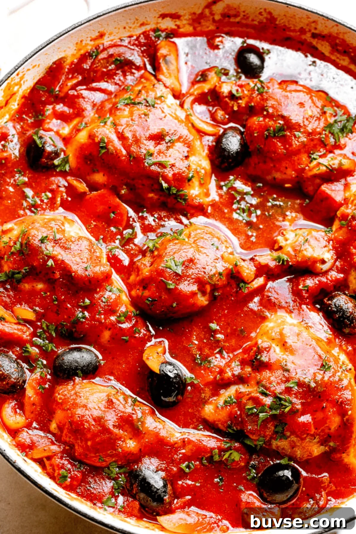 White ceramic pot with cooked chicken in tomato sauce.