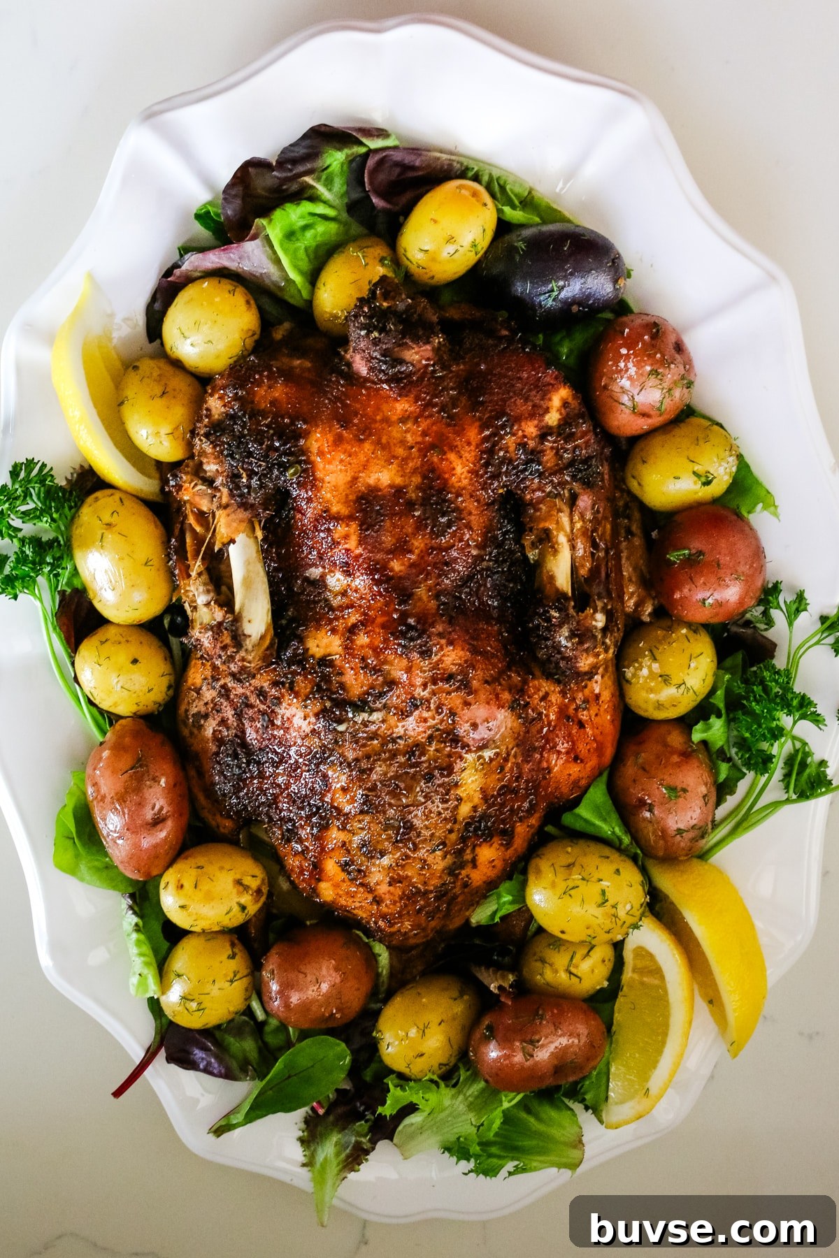 Slow Cooker Duck Recipe for Tender, Flavorful Meat 2 A wide shot of a seasoned duck with marble potatoes, lemon, and herbs.