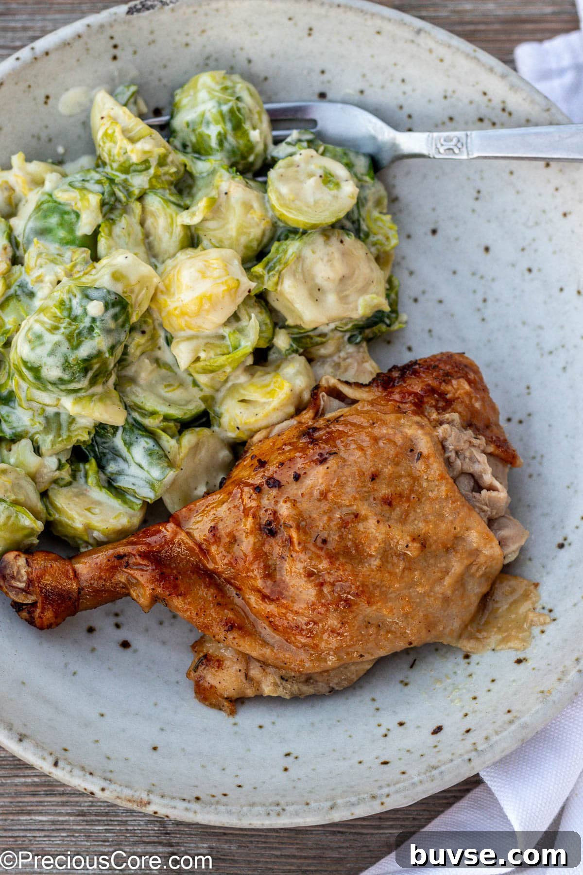 Herb Roasted Duck Recipe with Crispy Skin 4 Duck in a bowl with brussels sprouts.