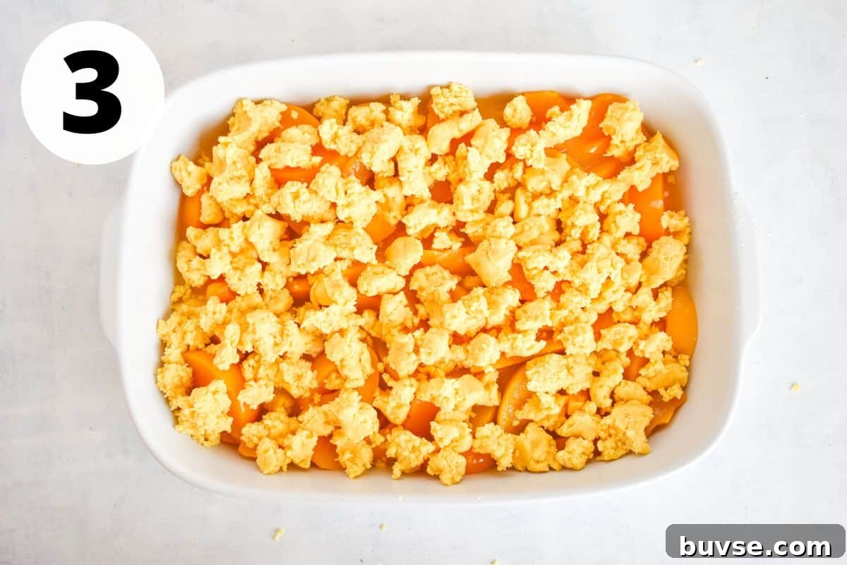 Quick Peach Cobbler with Canned Peaches and Cake Mix 6 cobbler topping being dropped on top of peaches.