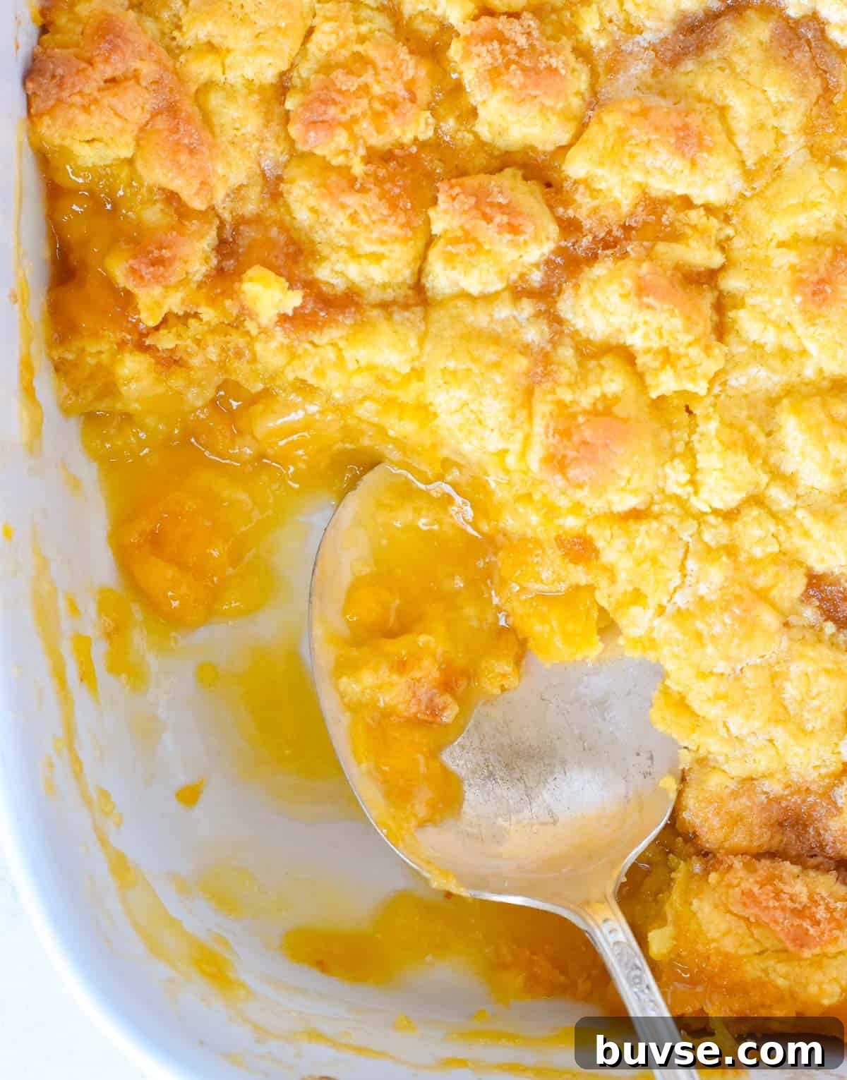 Quick Peach Cobbler with Canned Peaches and Cake Mix 7 serving spoon in partially eaten peach cobbler.