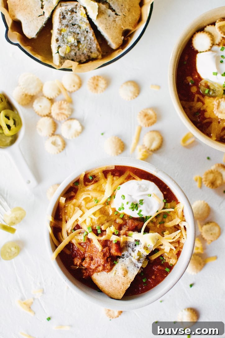 Spicy Texas Chili in two bowls surrounded by various toppings.