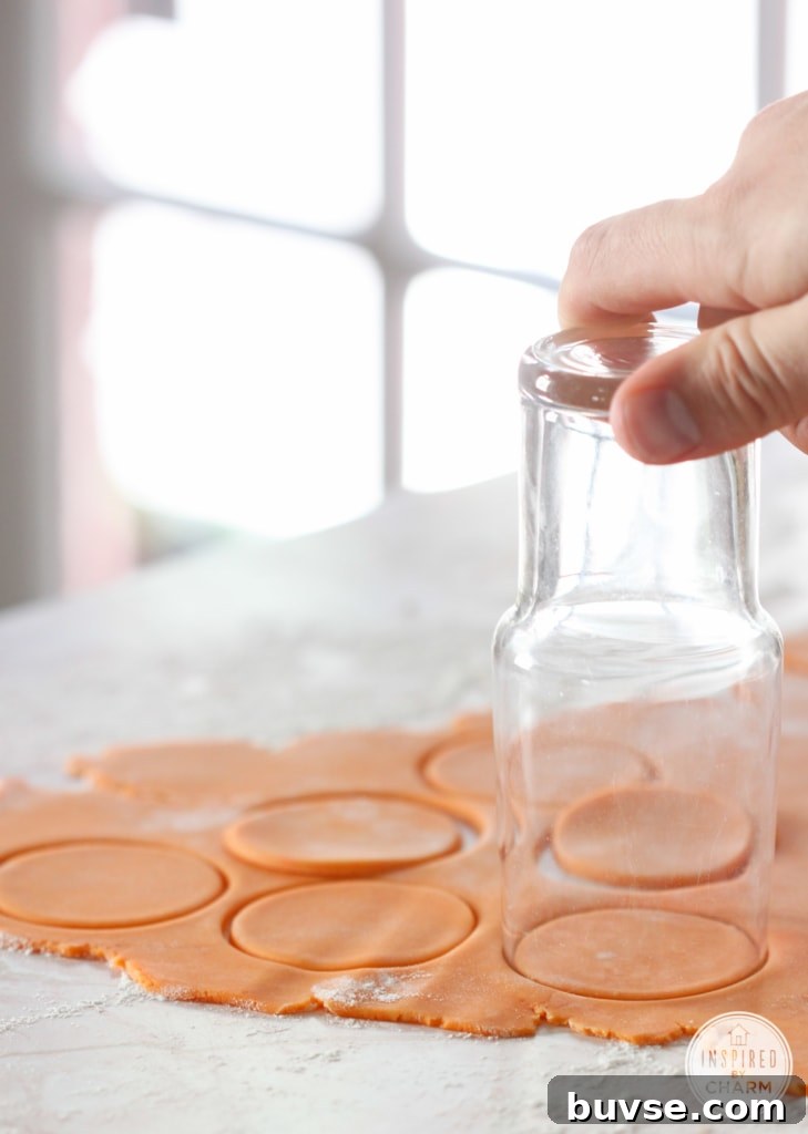 hand with a glass cutting out round cookies out of dough.