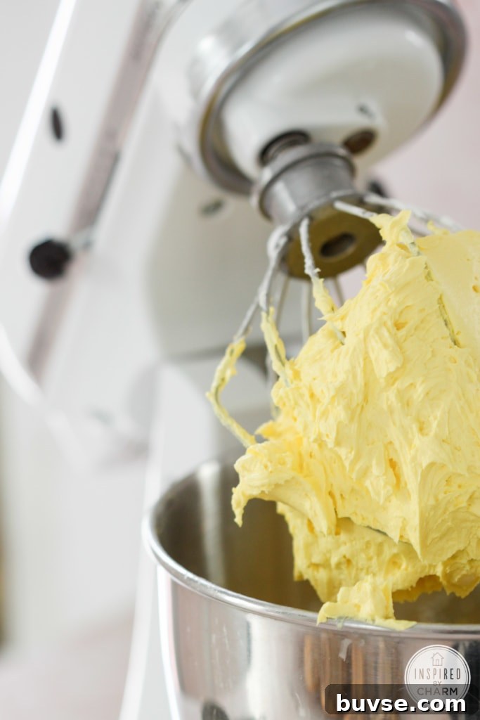white kitchen aid mixer with yellow frosting on whisk.